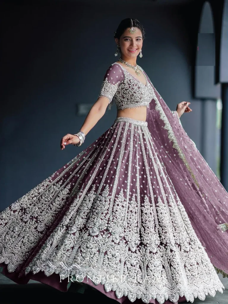 A Net Reception Lehenga features a delicate net fabric, often adorned with intricate embroidery or embellishments, offering a graceful and elegant look for receptions